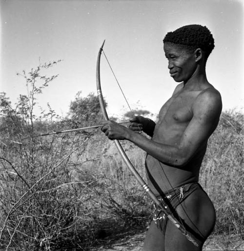 "/Qui Hunter" holding a bow and arrow, showing method of holding and releasing
