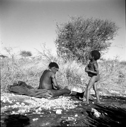 Woman washing herself, with a child standing next to her