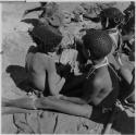 Children sitting, one playing a //guashi