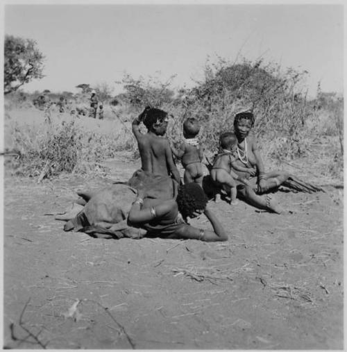 Group of women sitting, including !U and !Ungka (≠Toma's sister), with Lorna Marshall standing in background