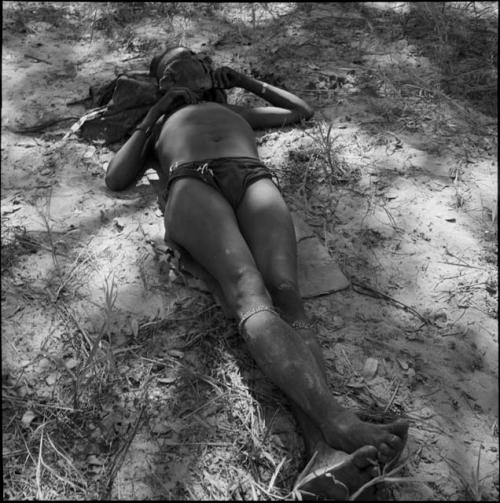 Man lying on the ground in the shade, with a cloth draped over his face