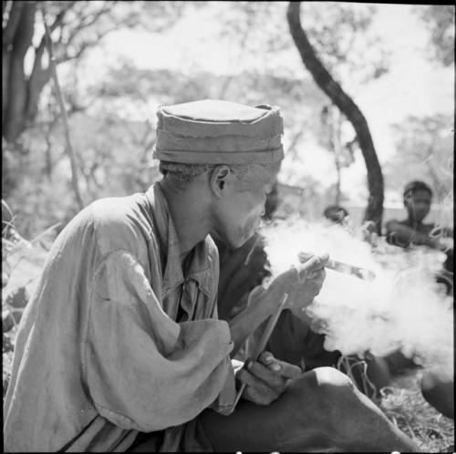 "Short /Qui" holding a file, smoking a cigar