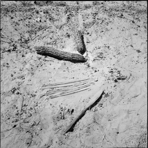 Fire paddle, arrows and two logs lying in the sand