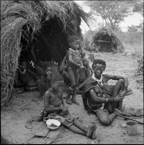 Boy cracking tsi from an enamel dish, sitting with his family in front of their skerm