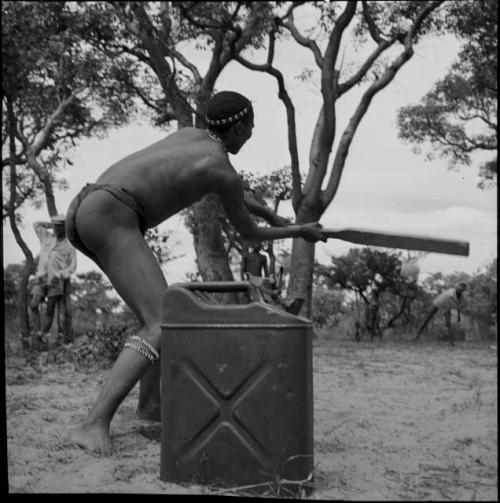 Man swinging a bat in a baseball game, next to a jerry can