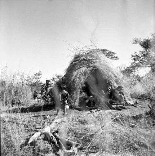 Group of people sitting in front of a skerm, with children standing on the other side of it