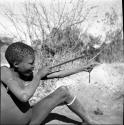 Gau's son shooting a slingshot made from a piece of an old inner tube