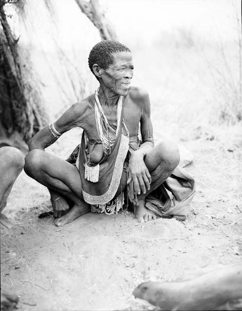 Di//khao (Gu!na) sitting, showing her beads and modesty apron