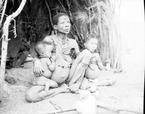 /Goishay (wife of ≠Gao, headman of Band 3) sitting in front of a skerm with her two youngest children, ≠Gisa and /Gasa