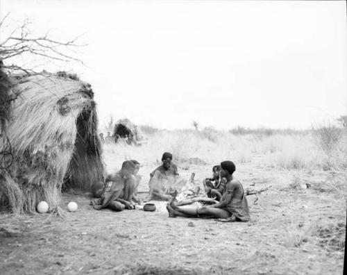 ≠Gao (brother of "Old Gau") sitting next to the ashes of a fire with his wife, Khwo//o-/Gasa (daughter of "Old /Gaishay"), their son, Gao, ≠Gisa, ≠Gisa's mother and Khuan//a (wife of //Ao and sister of Khwo//o-/Gasa)