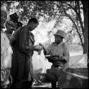 ≠Toma wearing Western clothing, handing tobacco to Venter, with John Marshall filming them