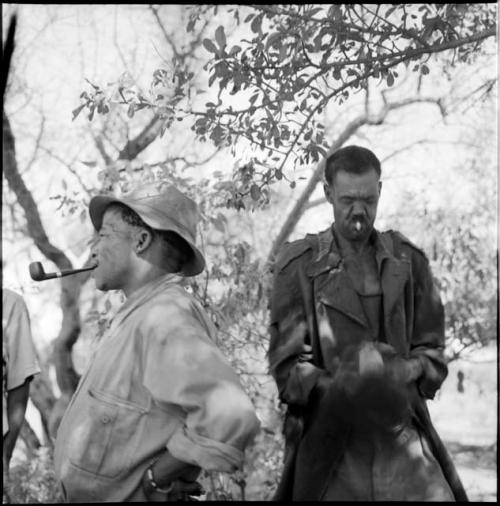 ≠Toma wearing Western clothing, smoking a pipe, standing next to Venter who is smoking a cigarette