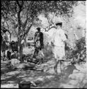 Group of men lying down and standing in the shade of a tree, with Venter standing in the back, bundle stored in the tree