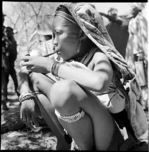 Woman wearing a cloth over her head and back, smoking a pipe, close-up