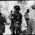 Venter holding a pipe, standing with a group of men