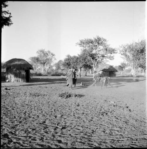 Two women working, with three women standing, watching, skerms in the background