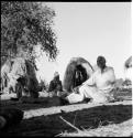 Two men and a woman sitting, with skerms in the background