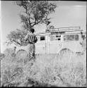 Man sitting on the top of the expedition Land Rover, with two men standing next to it