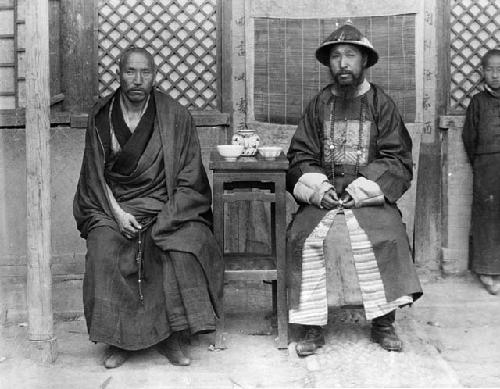 Two men seated on either side of small table
