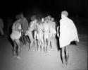 Group of boys dancing in a night dance, with a group of men dancing in a circle around them