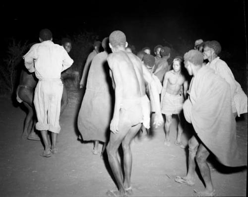 Ngani with a trance-like expression, dancing with others in a night dance