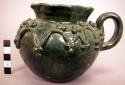 Ceramic green glazed handled jug with clay applique design.