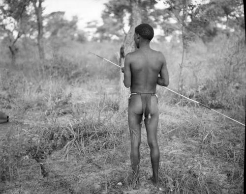 Man holding a spring-hare prodder, view from behind