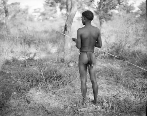 Man holding a spring-hare prodder, view from behind