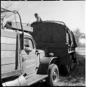 Man sitting in the back of one of two expedition trucks