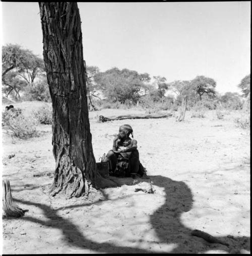 Woman sitting in the shade next to a tree