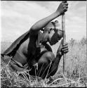 /Naoka digging for a root in the grass with her digging stick