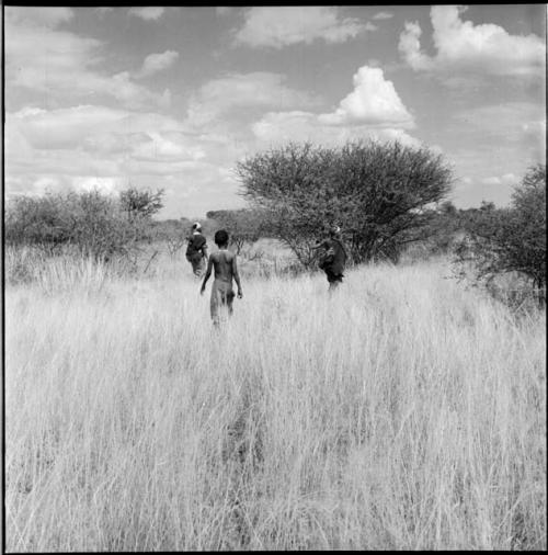 Two women and a girl gathering in the veld
