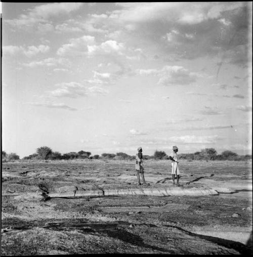 Two men standing at the edge of a pan, looking out over it