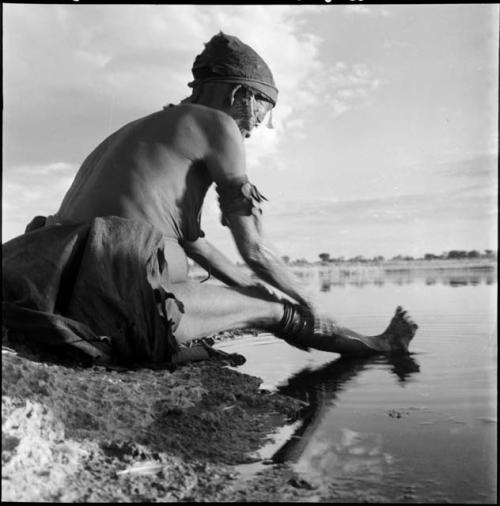 Di!ai sitting at the edge of a pan, washing her leg