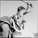 Woman beating mohengo with a pole, close-up