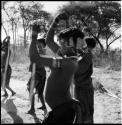 Women standing in a circle, beating mohengo with poles, close-up of part of the group