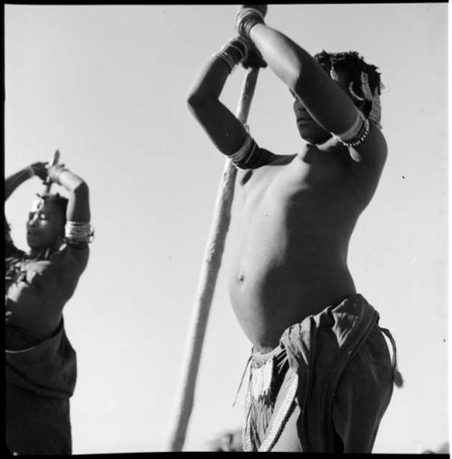 Two women beating mohengo with poles, close-up