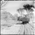 Two men sitting on top of expedition trucks, view from behind