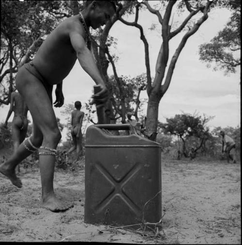 Man leaning a bat against a jerry can in a baseball game