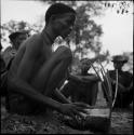 "/Gao Music" playing a //guashi, with a group of men sitting in the background, listening