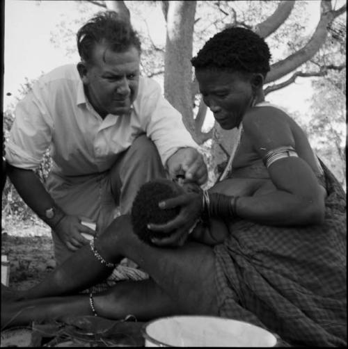 Woman holding a baby in her lap for Dr. Story to examine