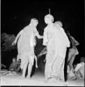 Two women dancing, one carrying a baby on her back, view from behind