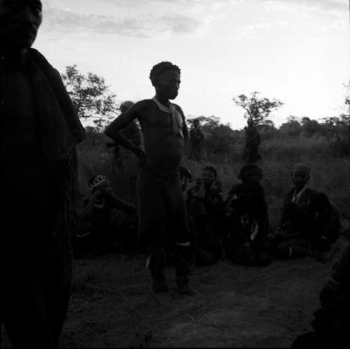 Group of people dancing at sunset, with a man standing, listening to the music