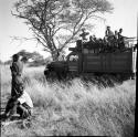 Group of people sitting and standing in the back of an expedition truck, with men standing and sitting near it