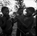 Three boys making a djani (helicopter toy) with sticks and feathers