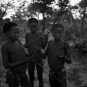 Three boys making a djani (helicopter toy) with sticks and feathers