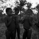 Three boys making a djani (helicopter toy) with sticks and feathers