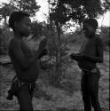 Two boys making a djani (helicopter toy) with sticks and feathers