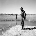 "Gao Medicine" standing at the edge of a pan after bathing, with another man standing in the distance behind him