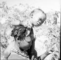Woman holding a child on her shoulder while she picks berries, close-up
